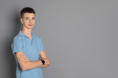 Portrait of teenage boy on grey background, space for text