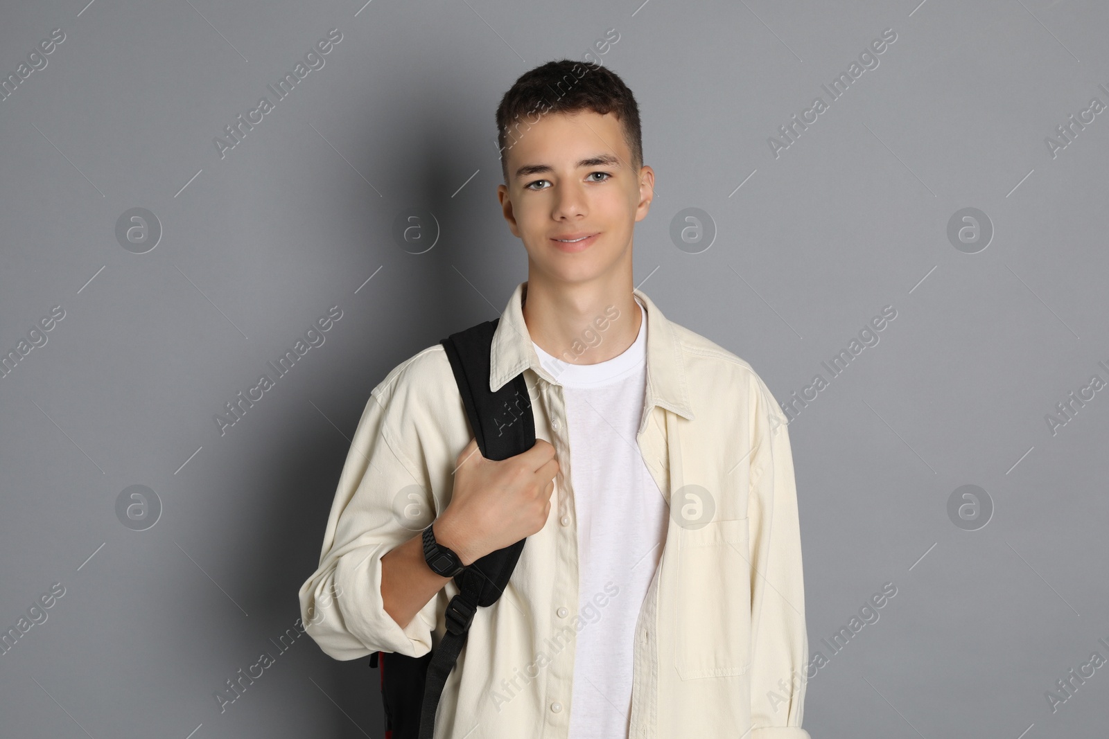 Photo of Portrait of teenage boy with backpack on grey background