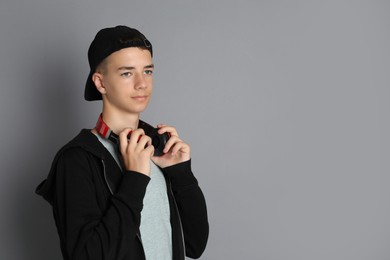 Photo of Portrait of teenage boy with headphones on grey background, space for text