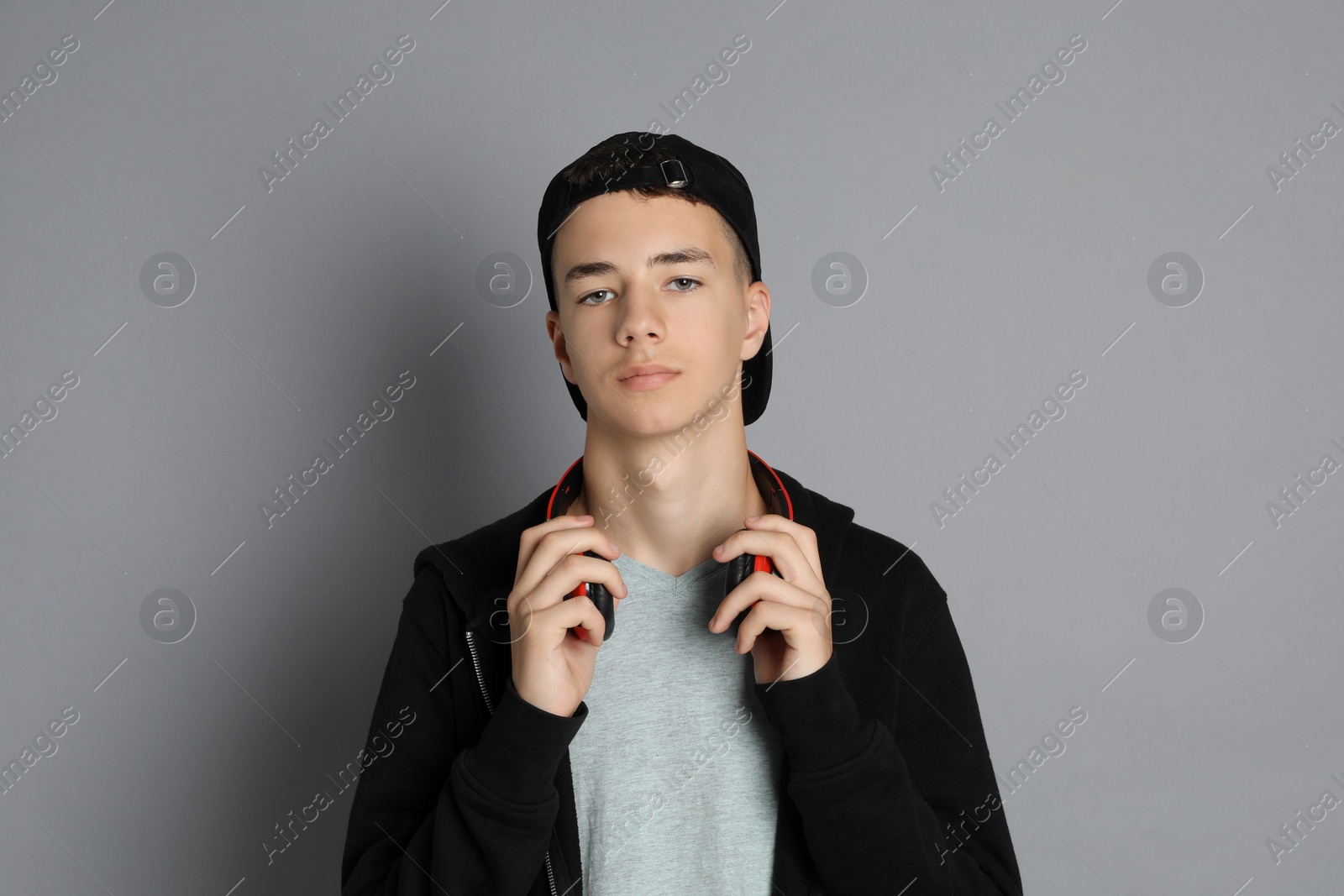 Photo of Portrait of teenage boy with headphones on grey background