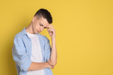 Photo of Portrait of thoughtful teenage boy on yellow background, space for text