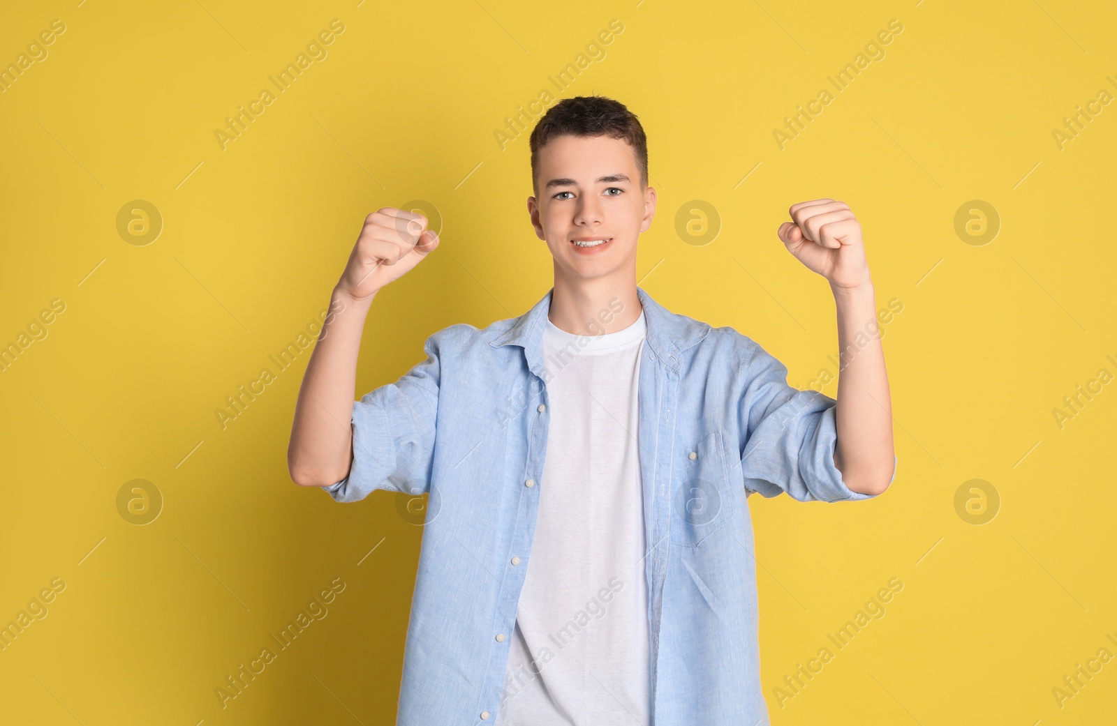 Photo of Portrait of happy teenage boy on yellow background