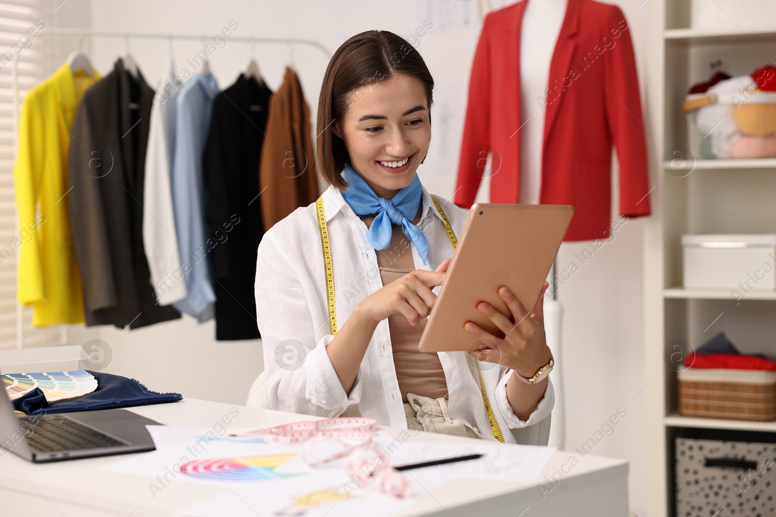 Photo of Fashion designer using tablet at table in workshop