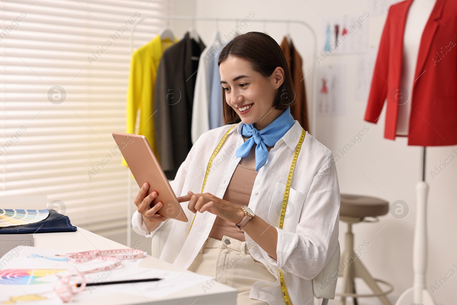 Photo of Fashion designer using tablet at table in workshop