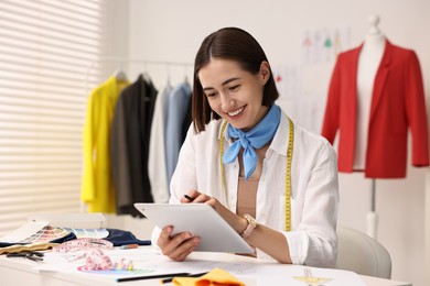 Photo of Fashion designer using tablet at table in workshop