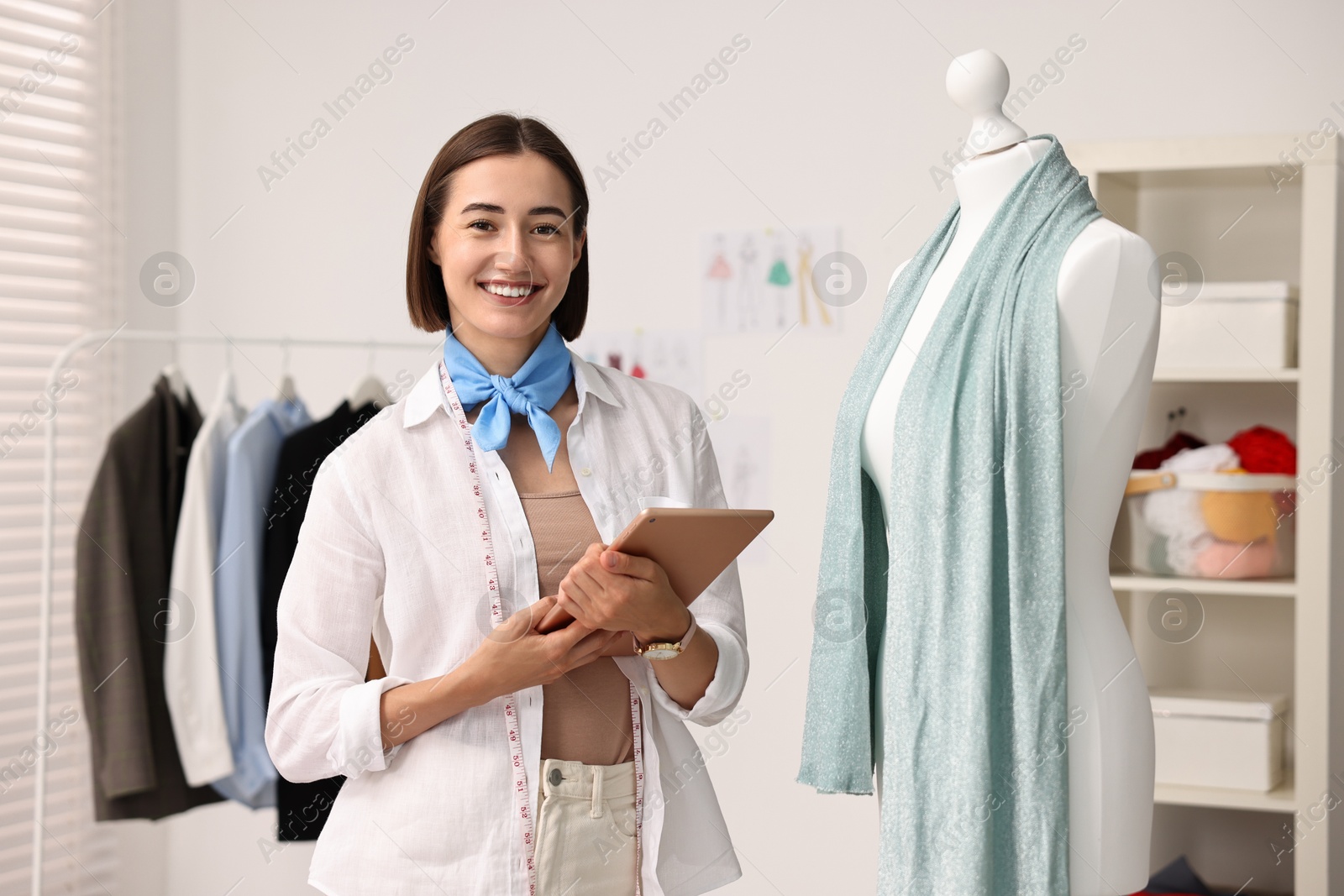 Photo of Happy fashion designer with tablet in workshop