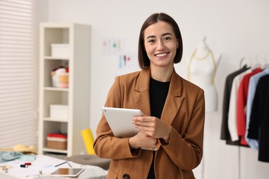 Photo of Happy fashion designer with tablet in workshop