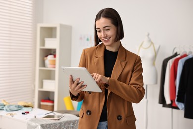 Photo of Happy fashion designer with tablet in workshop