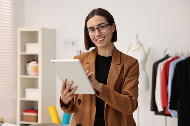 Happy fashion designer with tablet in workshop