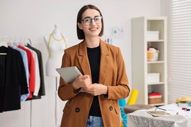 Happy fashion designer with tablet in workshop