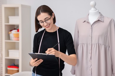 Photo of Fashion designer with clipboard working in workshop