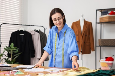 Fashion designer working at wooden table in workshop