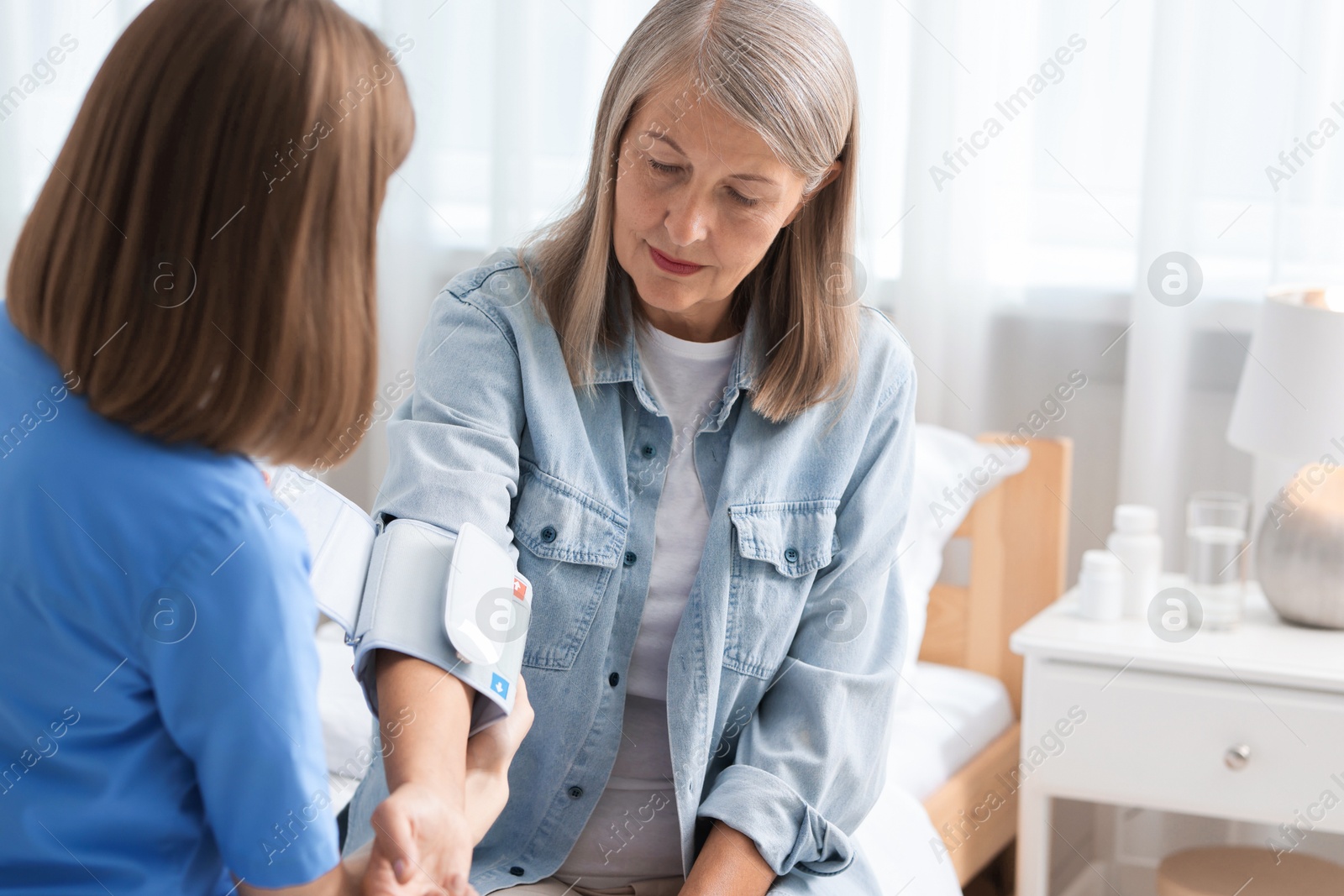 Photo of Healthcare worker measuring patient's blood pressure indoors