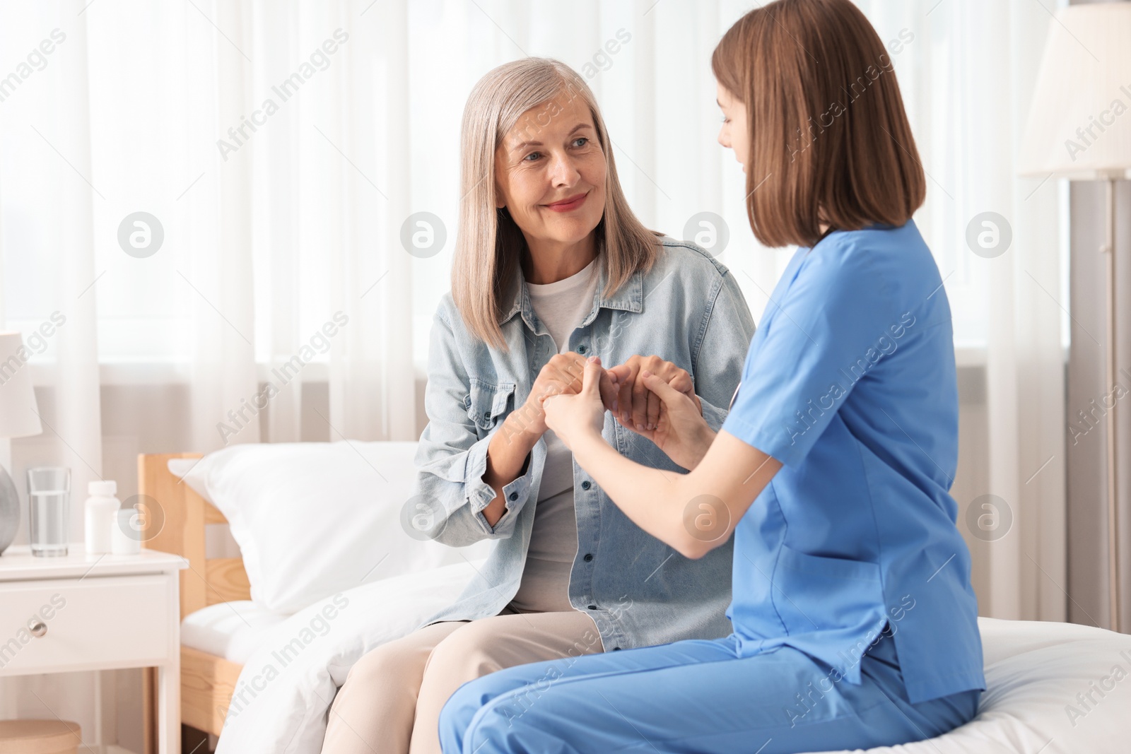 Photo of Healthcare worker supporting senior patient indoors. Space for text