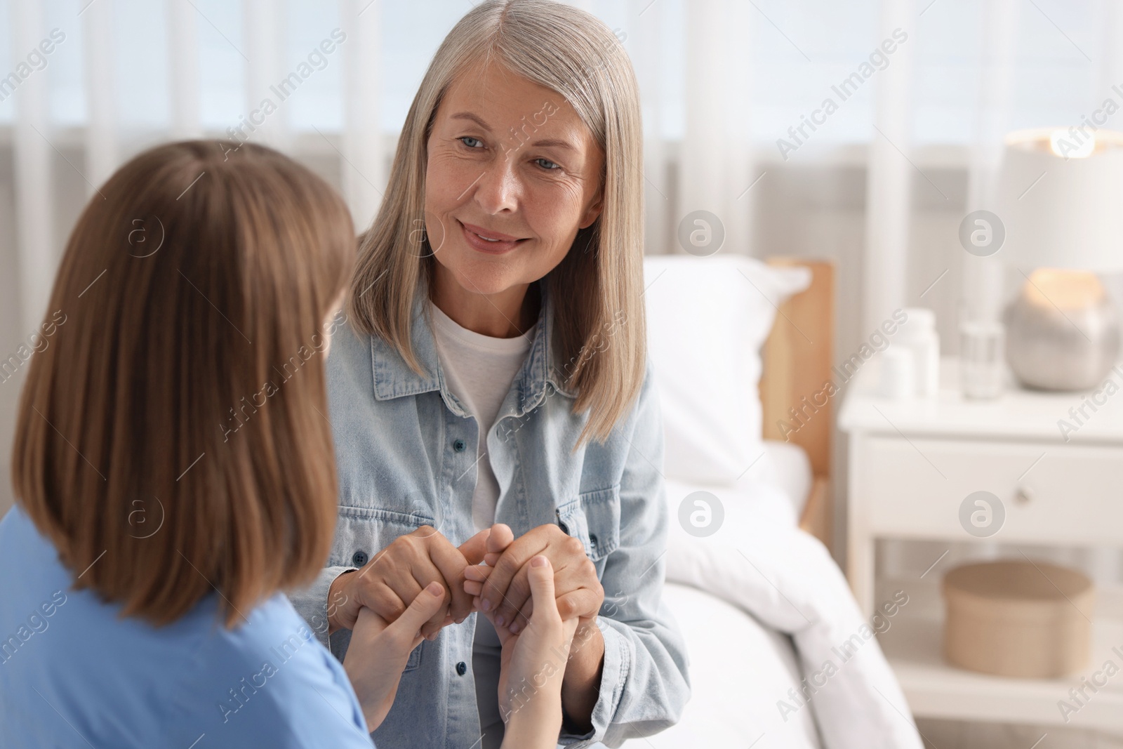 Photo of Healthcare worker supporting senior patient indoors. Space for text