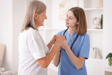 Young healthcare worker supporting senior patient indoors