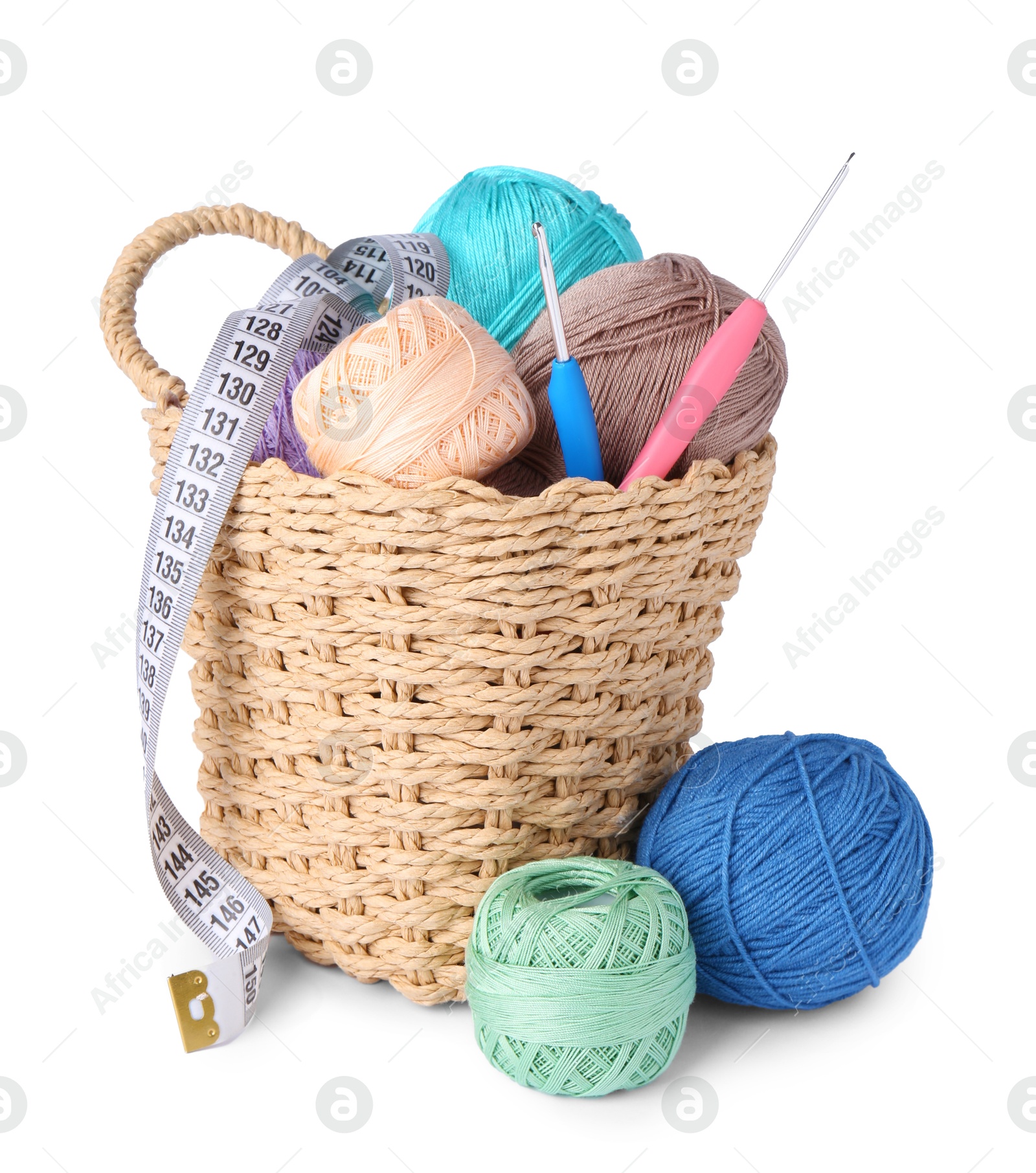 Photo of Colorful yarns, crochet hooks and measuring tape in wicker basket isolated on white