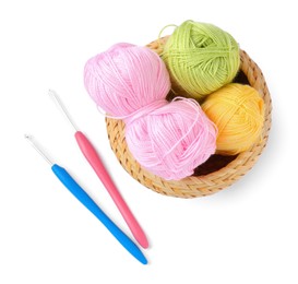 Photo of Colorful yarns and crochet hooks in wicker basket isolated on white, top view