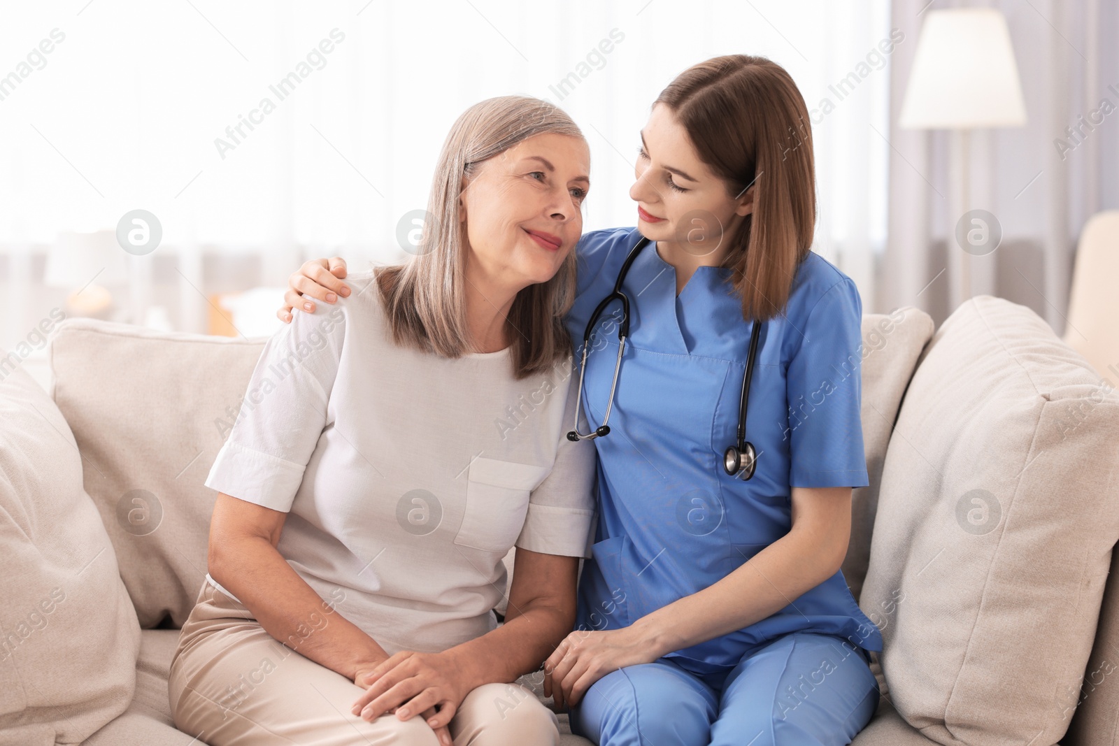 Photo of Young healthcare worker supporting senior patient indoors