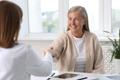 Smiling patient shaking hands with healthcare worker in hospital