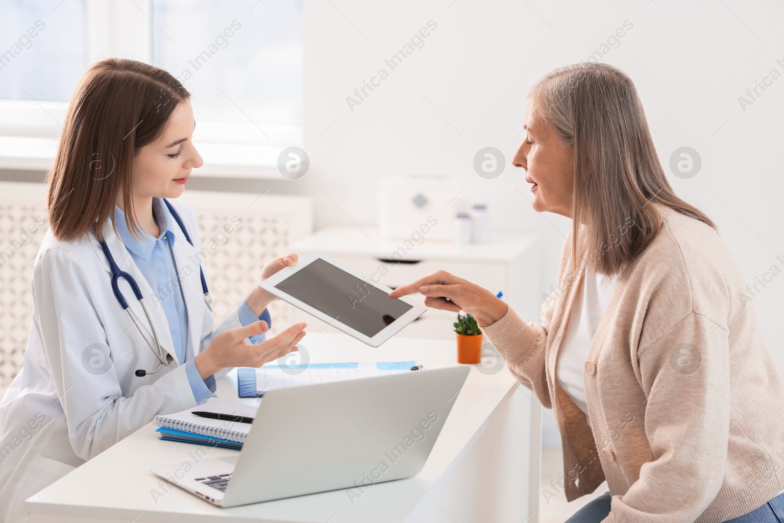 Photo of Healthcare worker and senior patient checking analysis results on tablet in hospital