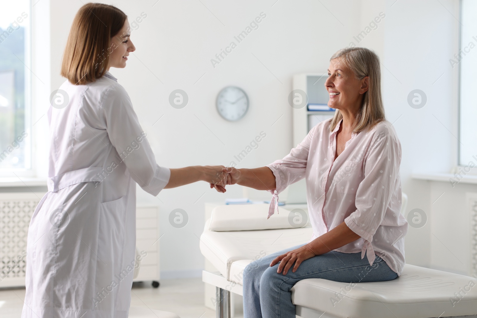 Photo of Smiling patient shaking hands with healthcare worker in hospital