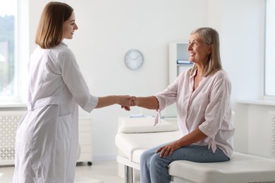 Smiling patient shaking hands with healthcare worker in hospital