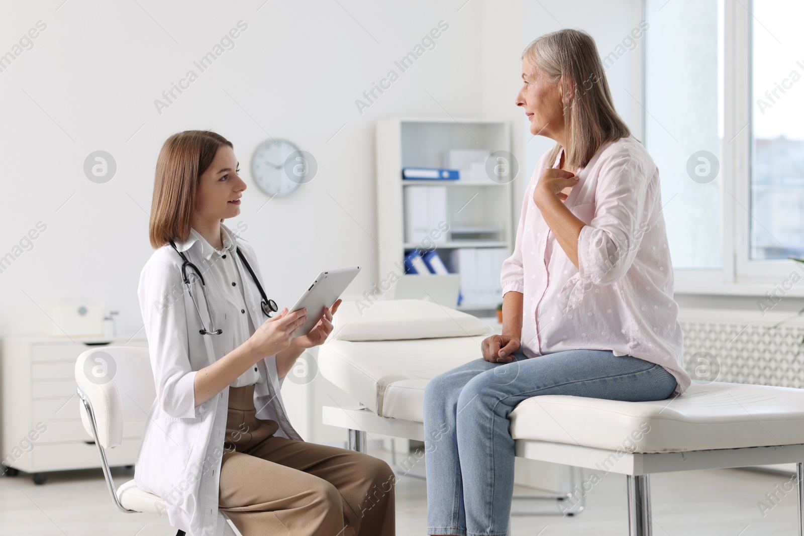 Photo of Smiling healthcare worker with tablet consulting senior patient in hospital