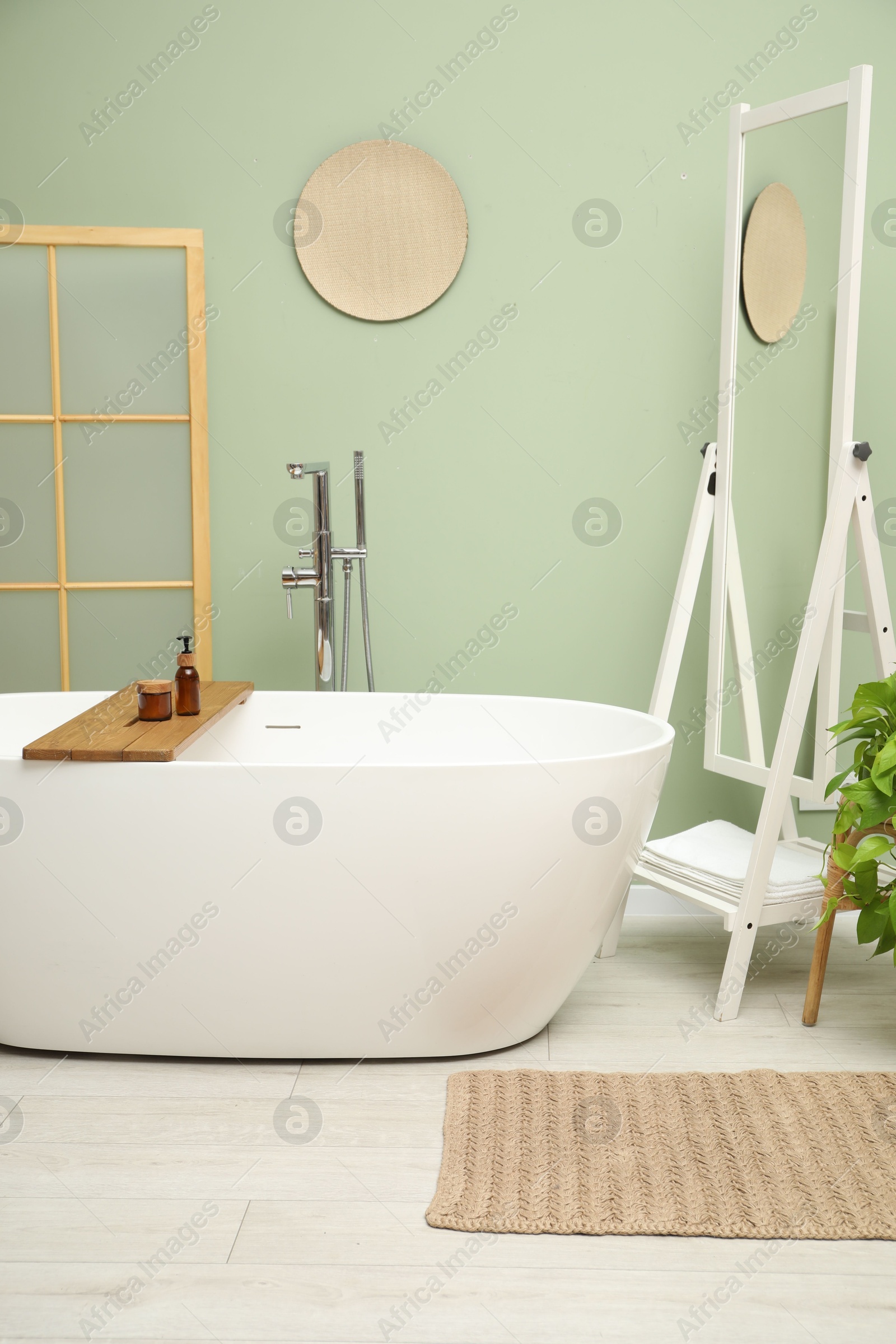 Photo of Stylish bathroom interior with folding screen and tub