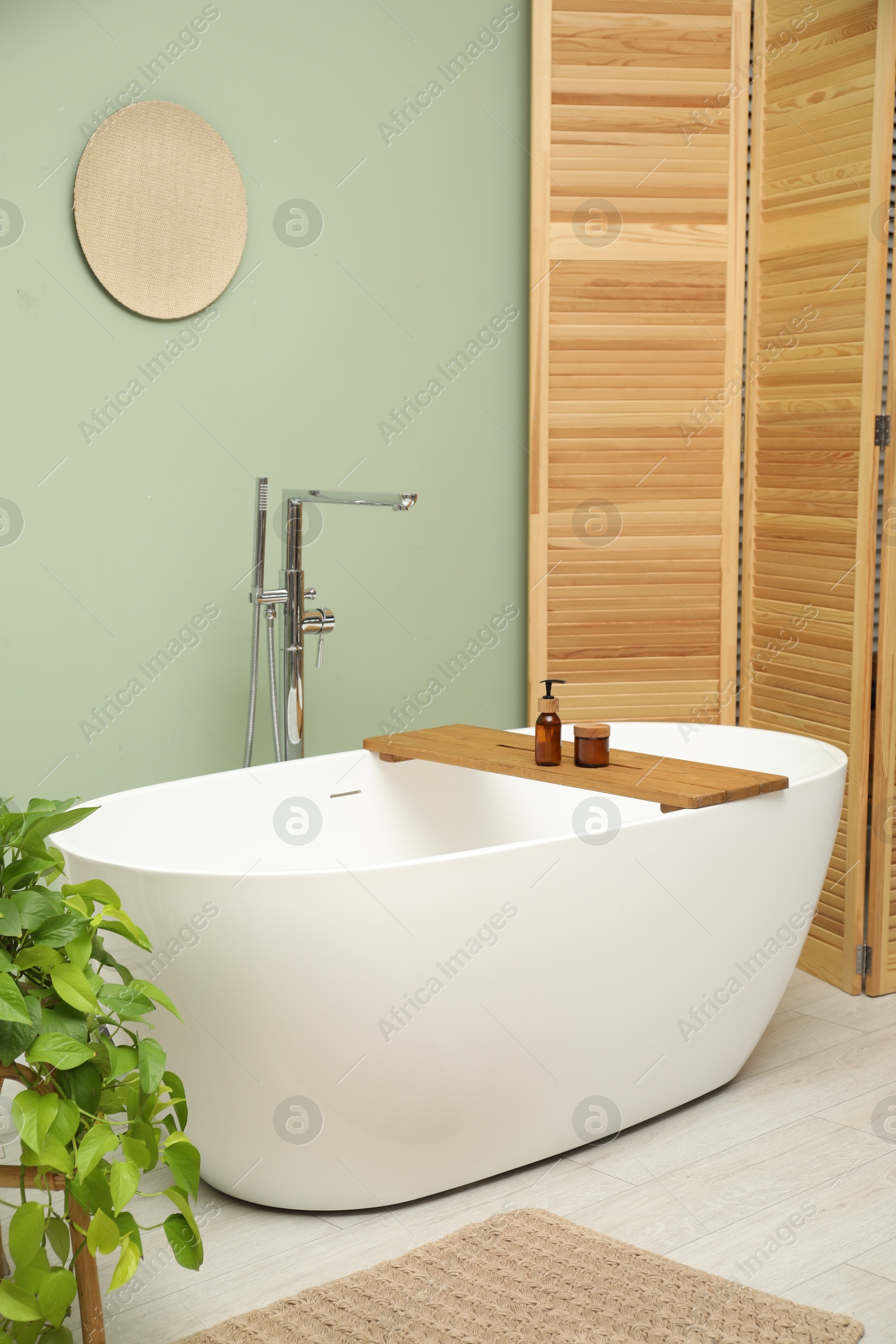 Photo of Stylish bathroom interior with folding screen and tub