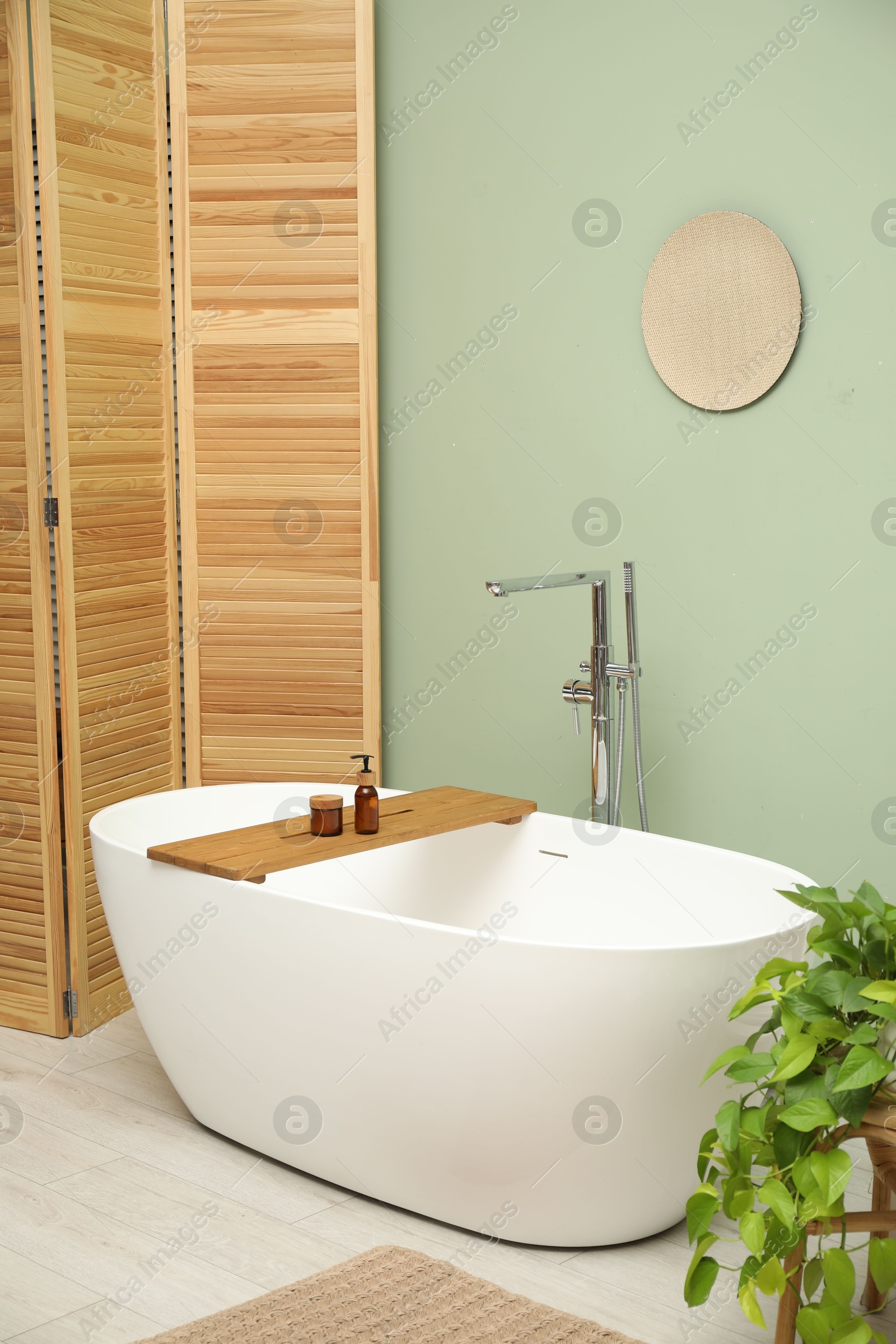 Photo of Stylish bathroom interior with folding screen and tub