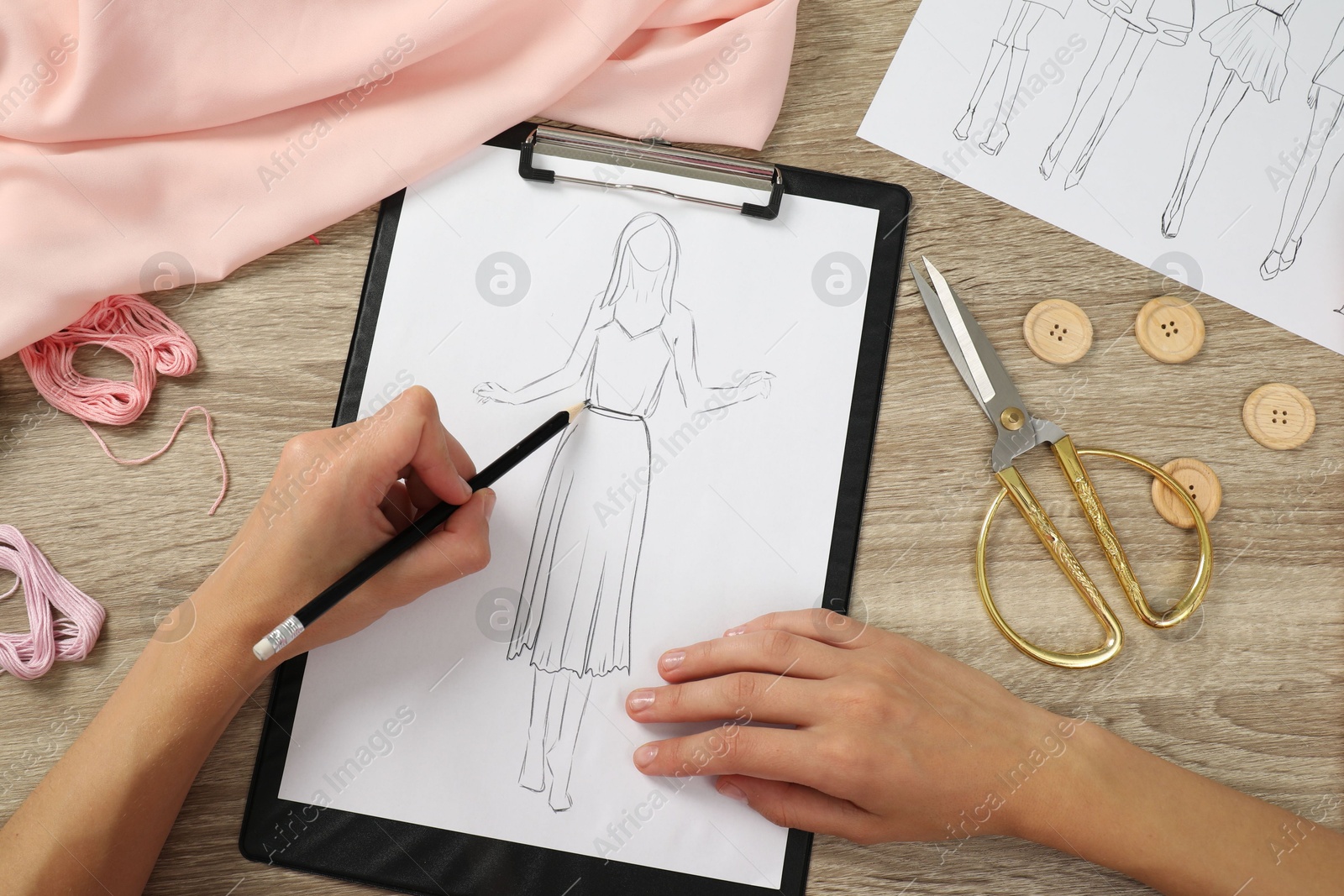 Photo of Fashion designer drawing sketch of stylish dress at wooden table, top view