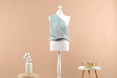 Mannequin with cloth, vase and stool on beige background