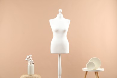 Female mannequin and vase on beige background