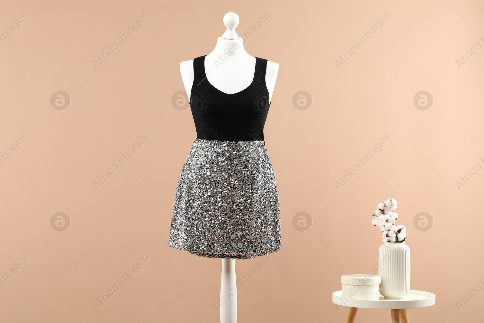 Photo of Mannequin with stylish dress and vase on beige background