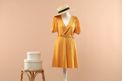 Mannequin with stylish dress and hat on beige background