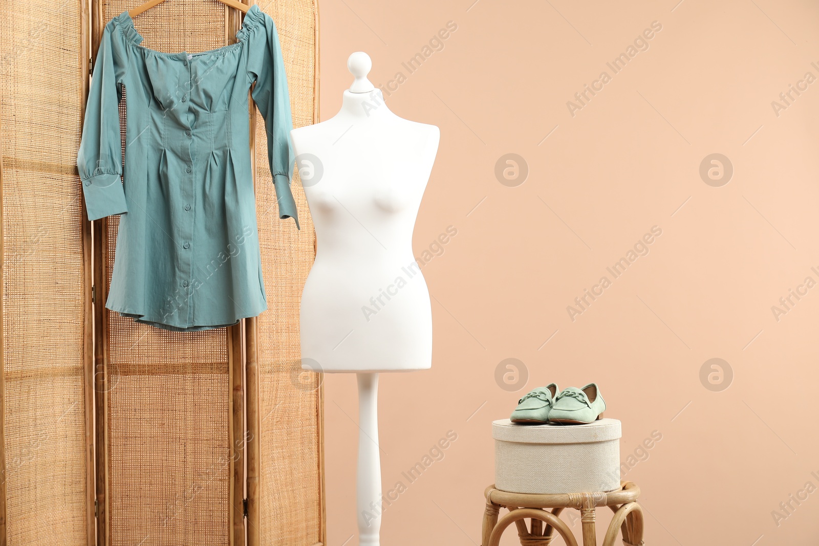 Photo of Mannequin with stylish dress, shoes, stool and folding screen on beige background