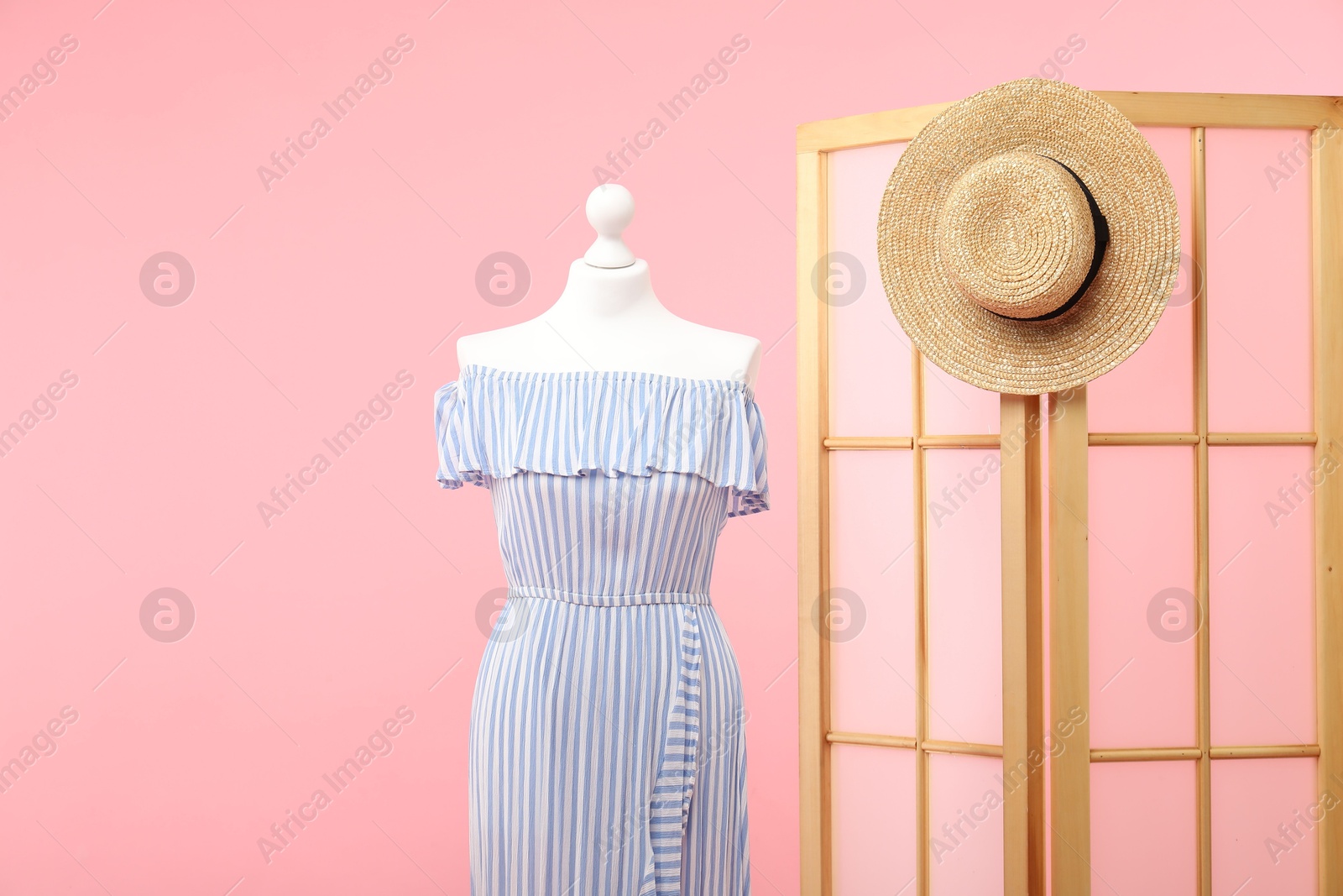 Photo of Mannequin with stylish dress, folding screen and hat on pink background