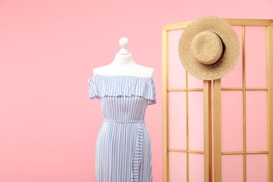 Photo of Mannequin with stylish dress, folding screen and hat on pink background