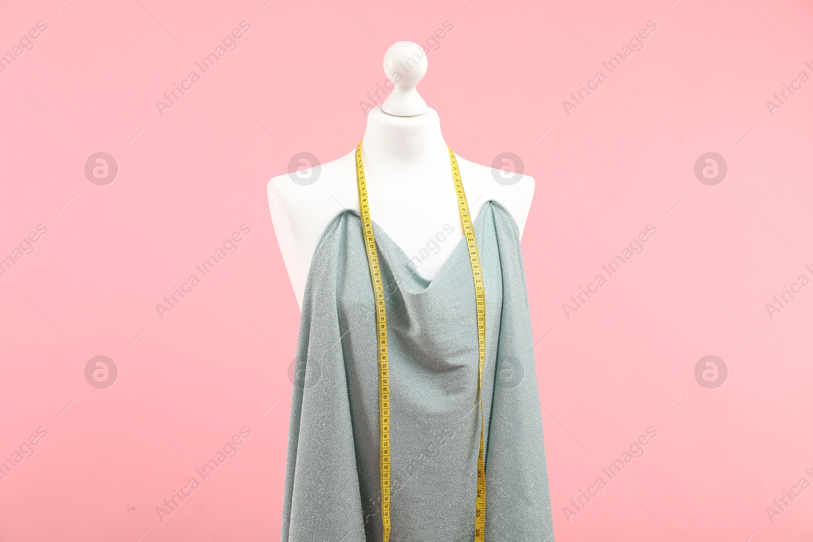 Photo of Mannequin, cloth and measuring tape on pink background