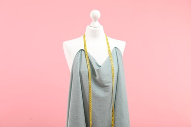 Photo of Mannequin, cloth and measuring tape on pink background