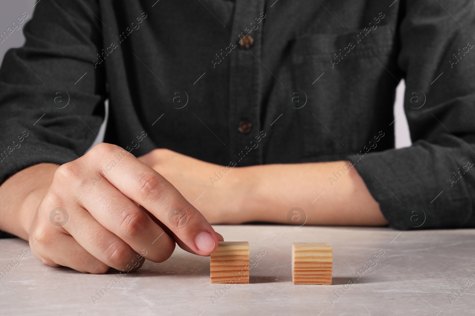 Photo of Woman with wooden cubes at light table, closeup