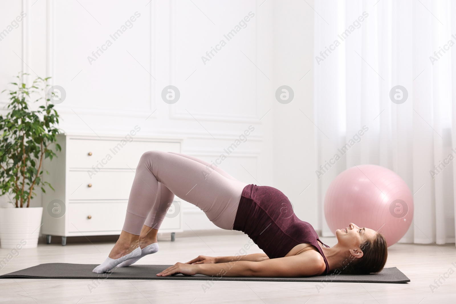 Photo of Beautiful pregnant woman doing stretching exercises on mat at home