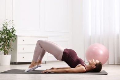 Beautiful pregnant woman doing stretching exercises on mat at home