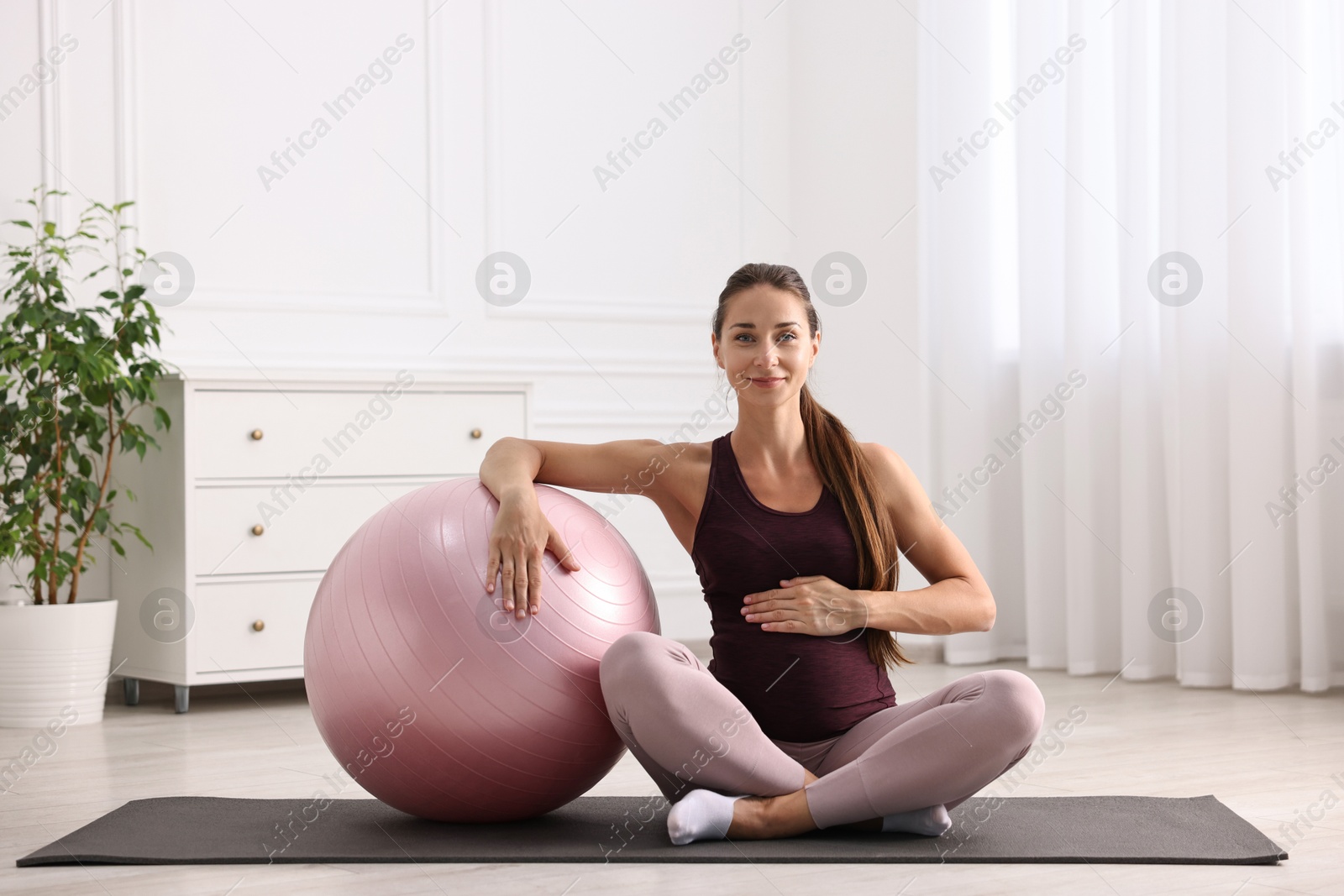 Photo of Beautiful pregnant woman with fitball on exercise mat at home