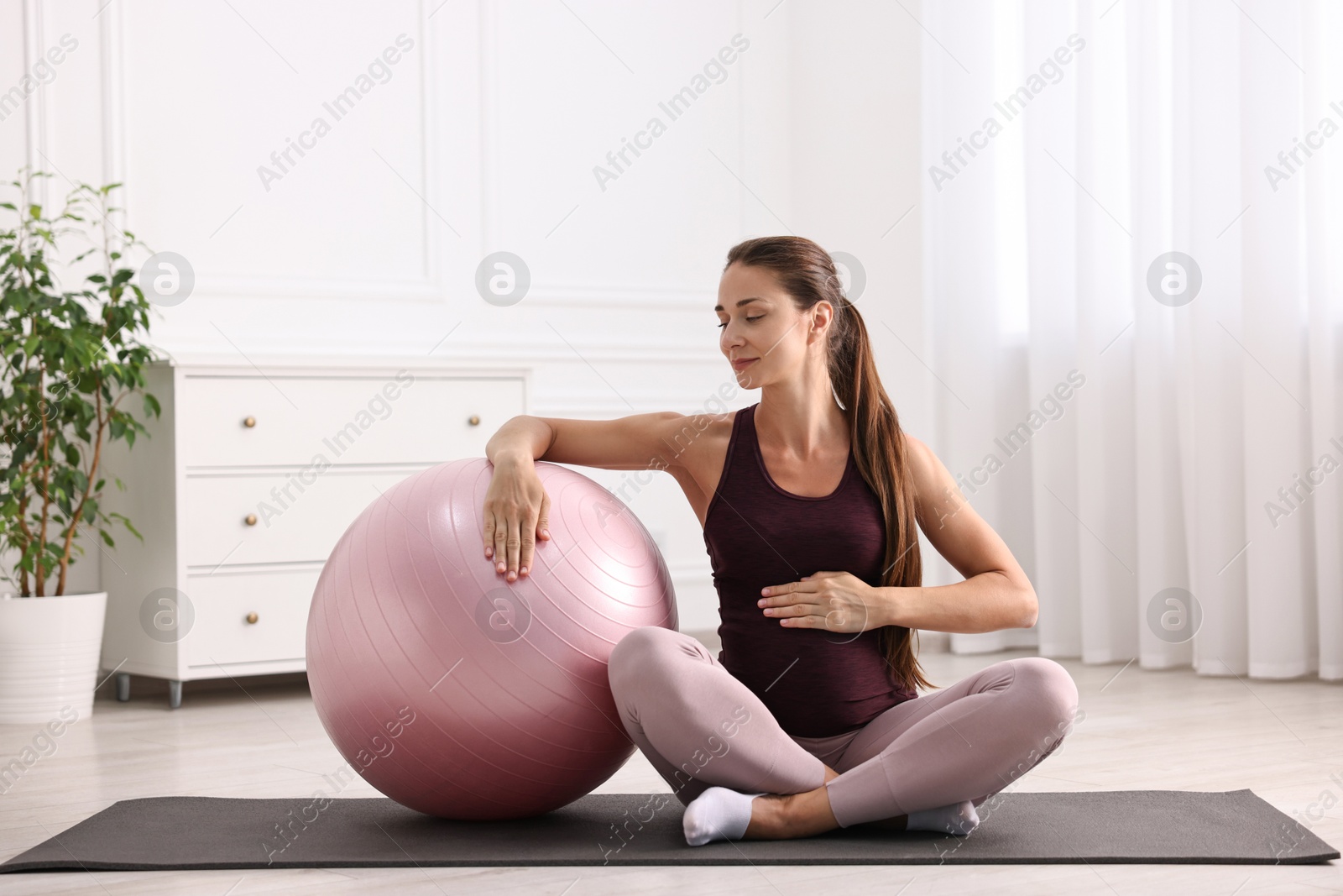 Photo of Beautiful pregnant woman with fitball on exercise mat at home