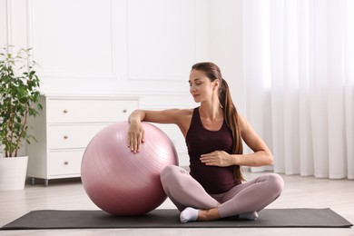 Photo of Beautiful pregnant woman with fitball on exercise mat at home