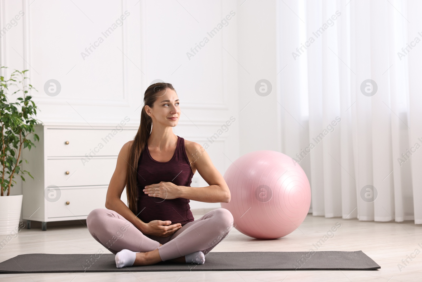 Photo of Beautiful pregnant woman with fitball on exercise mat at home