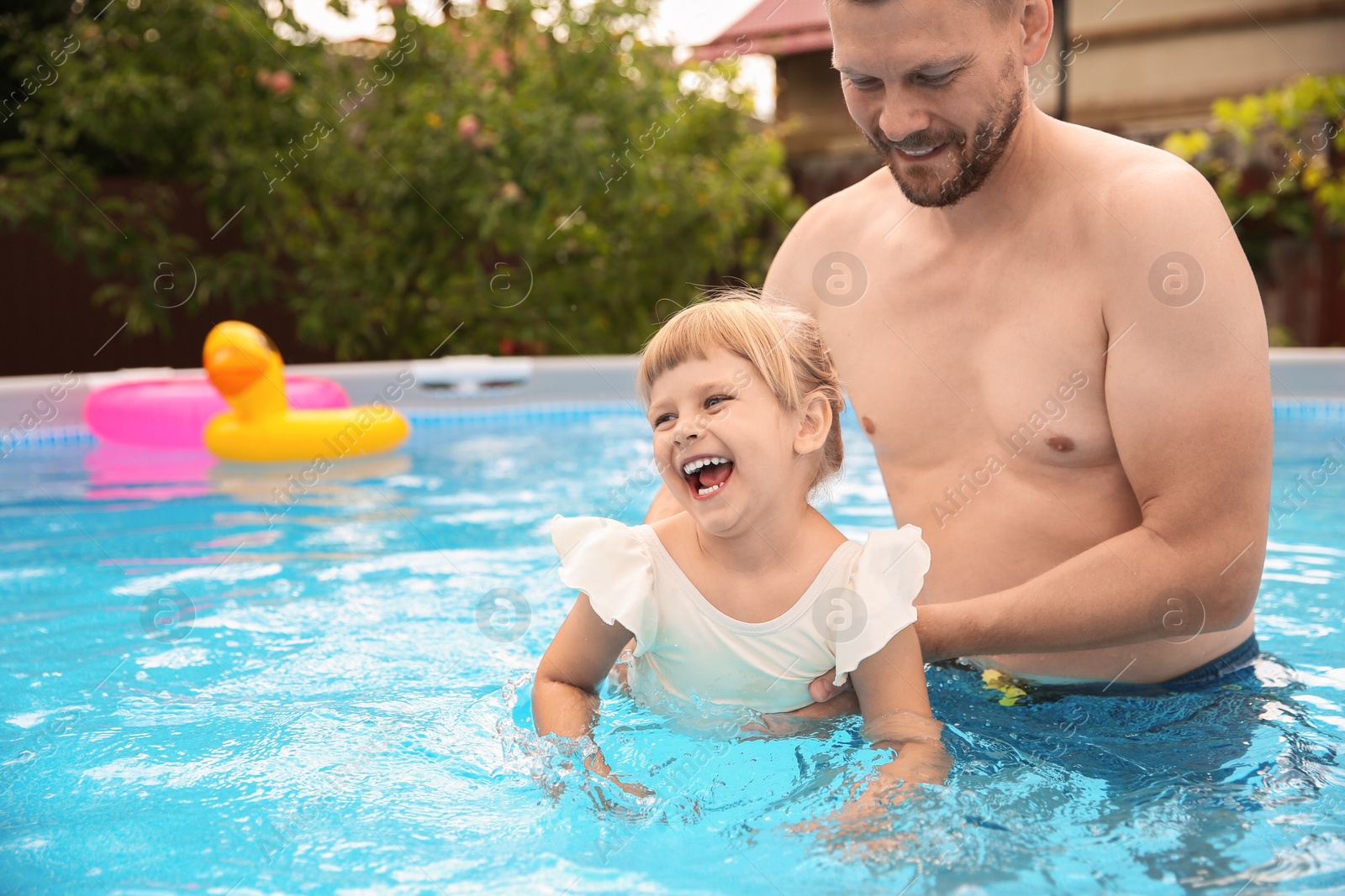 Photo of Happy daughter and her father having fun in swimming pool. Space for text