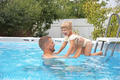 Happy daughter and her father having fun in swimming pool